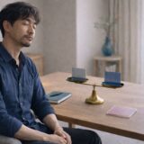 天秤の前で目を閉じ、静かに判断を整理している40代男性の様子