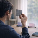 医療脱毛で何を優先するか考えながら、複数の選択肢を手に取って判断している40代男性の様子