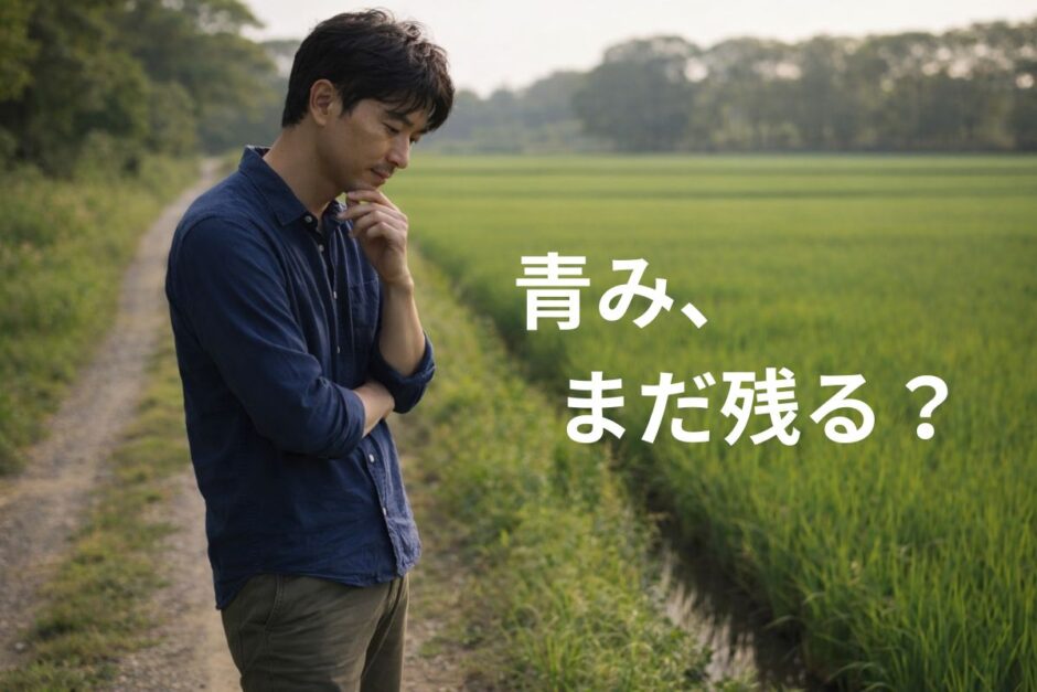 田んぼ道を歩く途中で立ち止まり、顎に手を当てて少し考える40代男性の様子